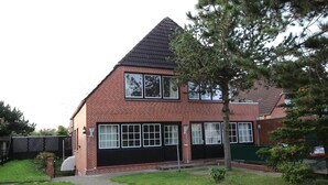 Une maison à deux étages, construite en briques, avec un toit noir, de grandes fenêtres et une porte de garage bien visible.