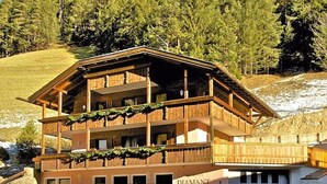 Un edificio de madera de varios pisos con balcones, identificado como "DIAMANT", con montañas al fondo.