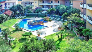 Un hôtel doté d’une piscine entourée d’une végétation luxuriante et de nombreux balcons.