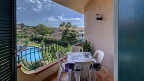 Un balcon avec une table et des chaises, donnant sur une piscine et un quartier résidentiel.