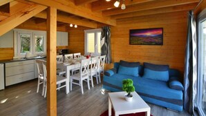 Ein gemütliches Blockhaus-Interieur mit Essbereich, einem blauen Sofa und einem roten Teppich.