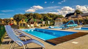 Ein Swimmingpool mit Liegestühlen, einer Wasserrutsche und einer Springbrunnen.