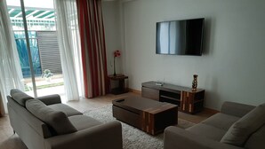 A modern living room with two sofas, a coffee table, a TV, and a sliding glass door to a balcony. - Executive D2W suites and residences (machakos)