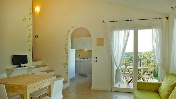 Un coin repas avec une table et des chaises, une cuisine en arrière-plan et un balcon avec vue.