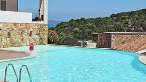 Une piscine avec un mur en pierre et vue sur la mer.