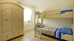 Une chambre avec un lit superposé, une armoire et une fenêtre avec des rideaux.