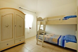 A bedroom with a bunk bed, a wardrobe, and a window with curtains.