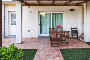 A patio with a table and chairs, a sliding glass door, and a small garden area.