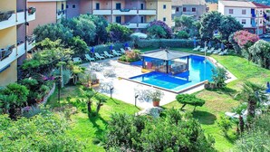 Ein Hotel mit Swimmingpool, Liegestühlen und viel Grün.