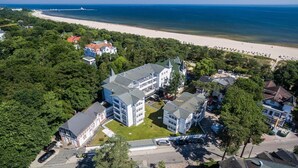 An aerial view of a coastal hotel with multiple buildings, a beach, and a pier in the background.