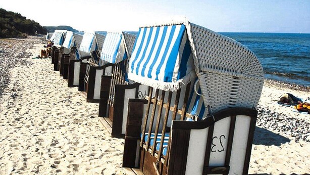 Beach huts with striped awnings lined up along the shore.