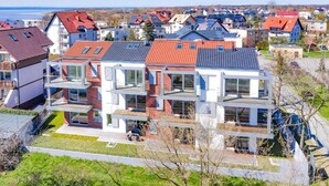 A modern residential building with multiple floors, large windows, and a flat roof.