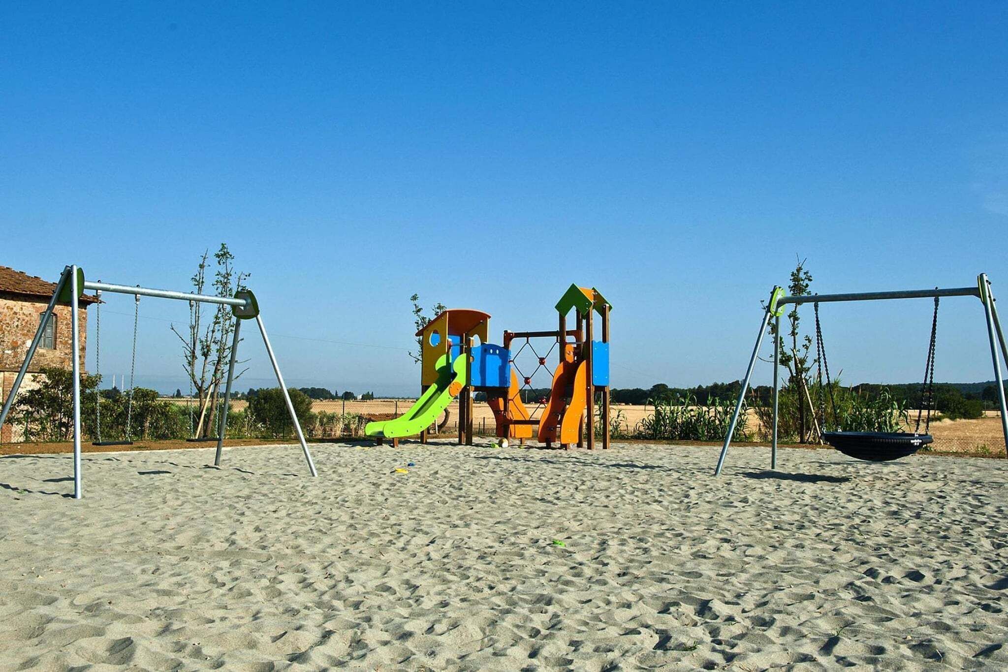 Un'area giochi con altalene e scivoli su una spiaggia sabbiosa.