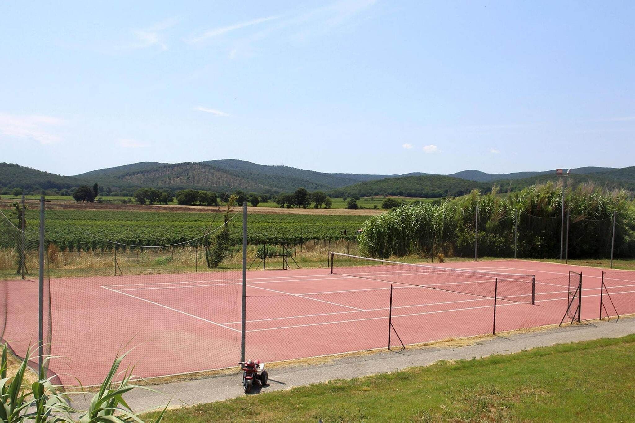 Un court de tennis entouré de champs verdoyants et de collines.