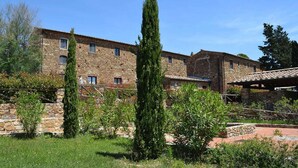 Un edificio de piedra con múltiples ventanas y un patio con vegetación.