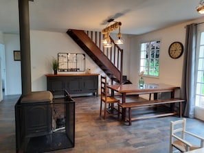 Una cocina moderna con una escalera de madera, una mesa de comedor con bancos y un amplio ventanal con vistas al verdor.