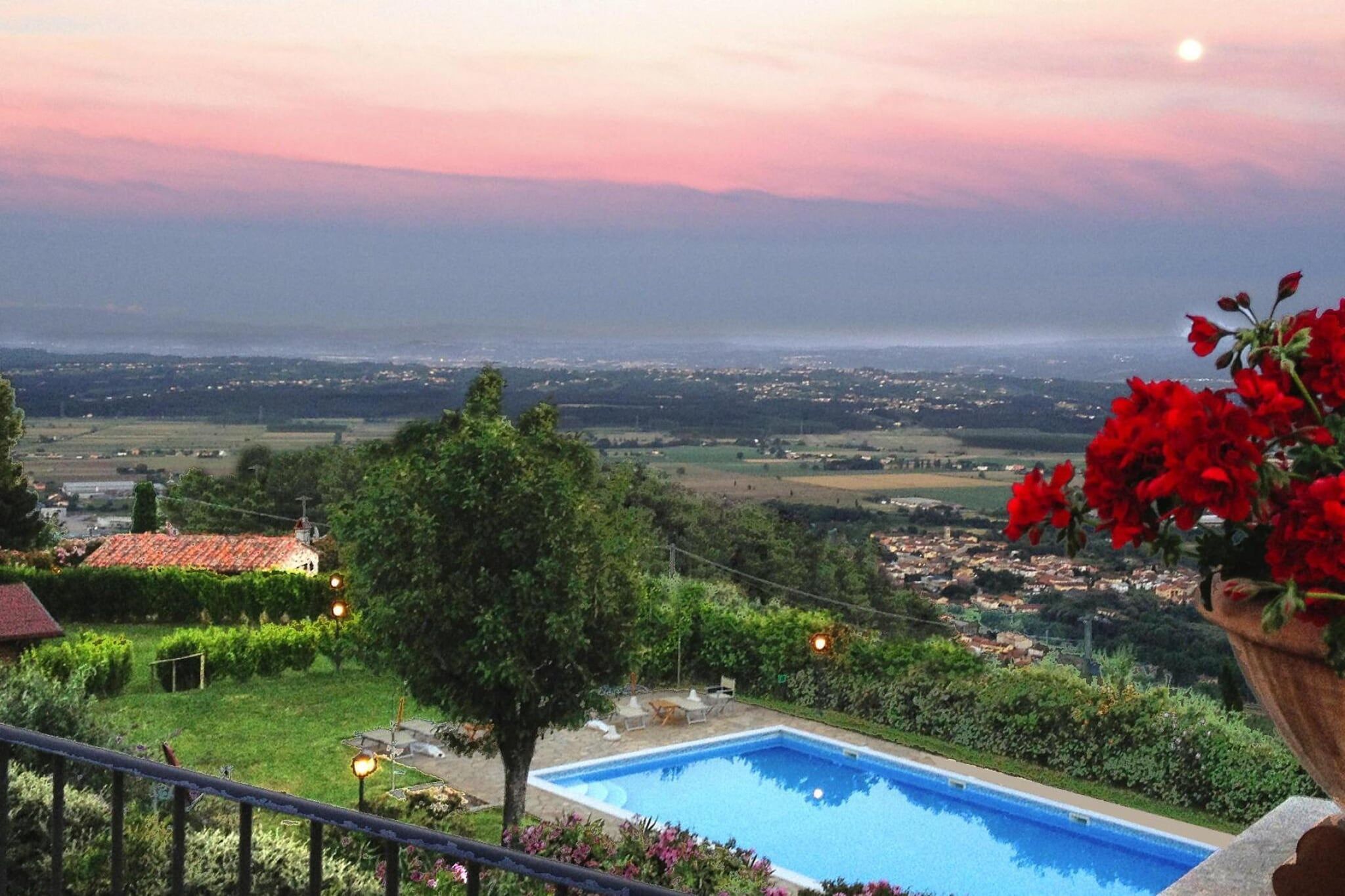 Una piscina con vista su una città e campi, immersa nel verde e un albero.