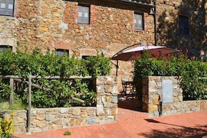 A stone building with a patio area, outdoor seating, and a wooden fence. - Apartment in Campiglia Marittima (Campiglia Marittima)