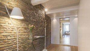 A modern room with a stone wall, a glass table with a vase, and a white lamp.