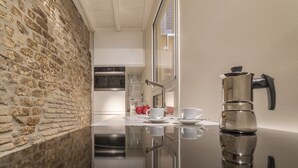 A modern kitchen with a stone wall, stainless steel appliances, and a reflective countertop.