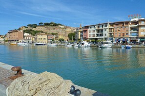 A marina with boats docked, a hotel named 'HOTEL LAPPRODO' in the background, and a historic building on a hill.