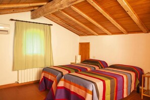 A room with two beds, a window with a curtain, a radiator, and a wooden ceiling.