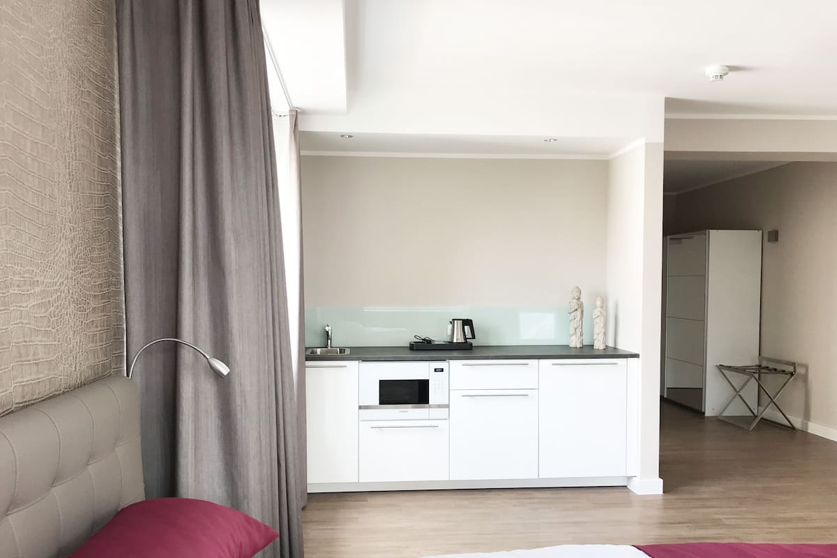 Ett modernt hotellrum med en säng, ett litet pentry och ett badrum som syns i bakgrunden.