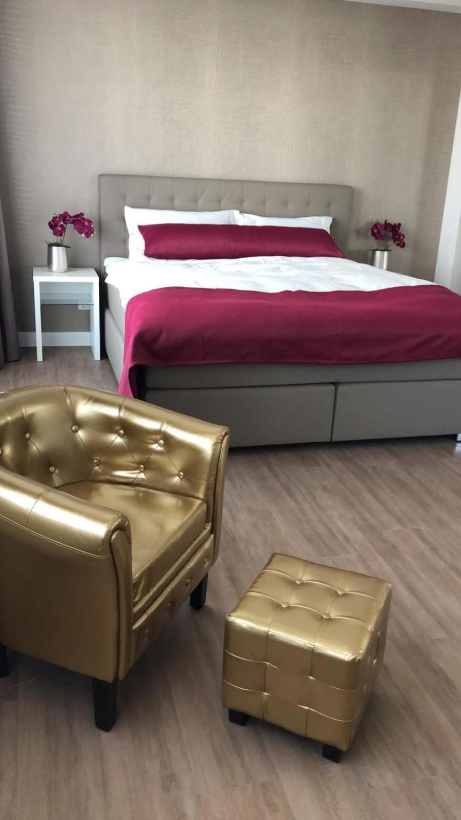 A bedroom with a bed, a gold armchair, and a gold ottoman.