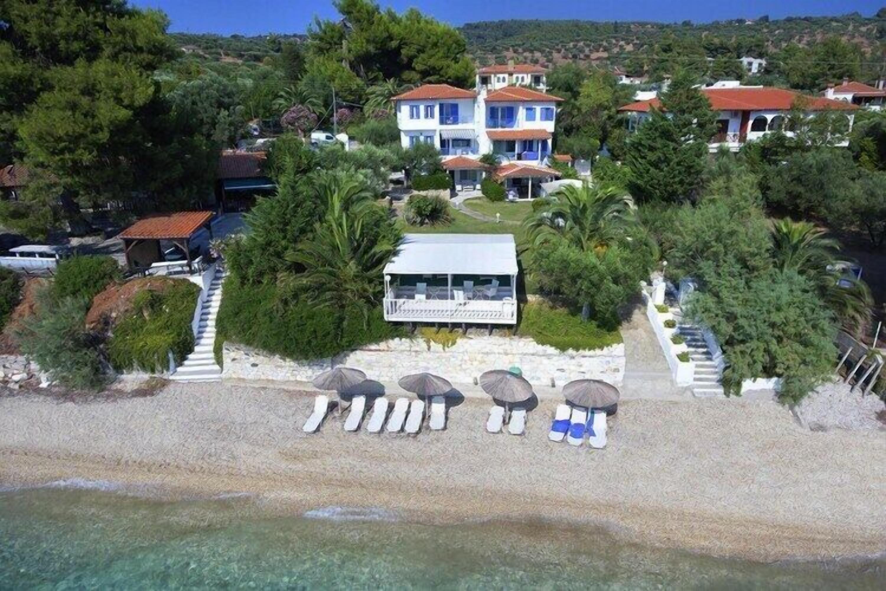 Una proprietà costiera con spiaggia, ombrelloni e un edificio a più piani.