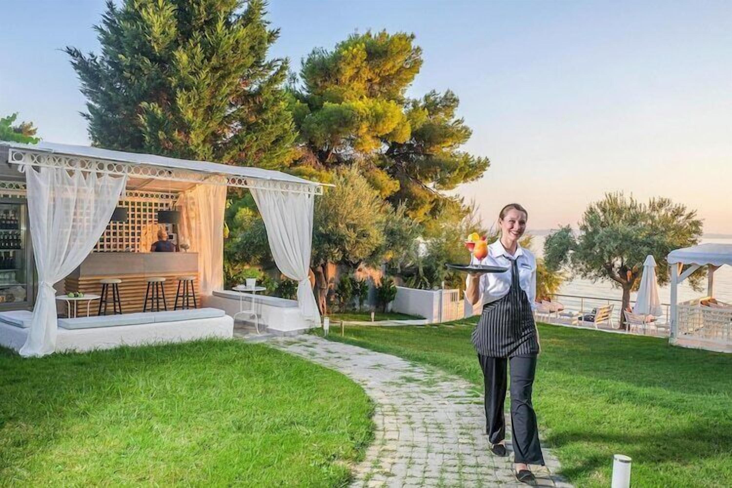 Un'area esterna curata con un'area salotto coperta, un vialetto e vegetazione lussureggiante.