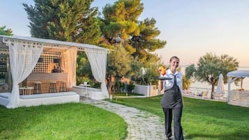 Un'area esterna curata con un'area salotto coperta, un vialetto e vegetazione lussureggiante.