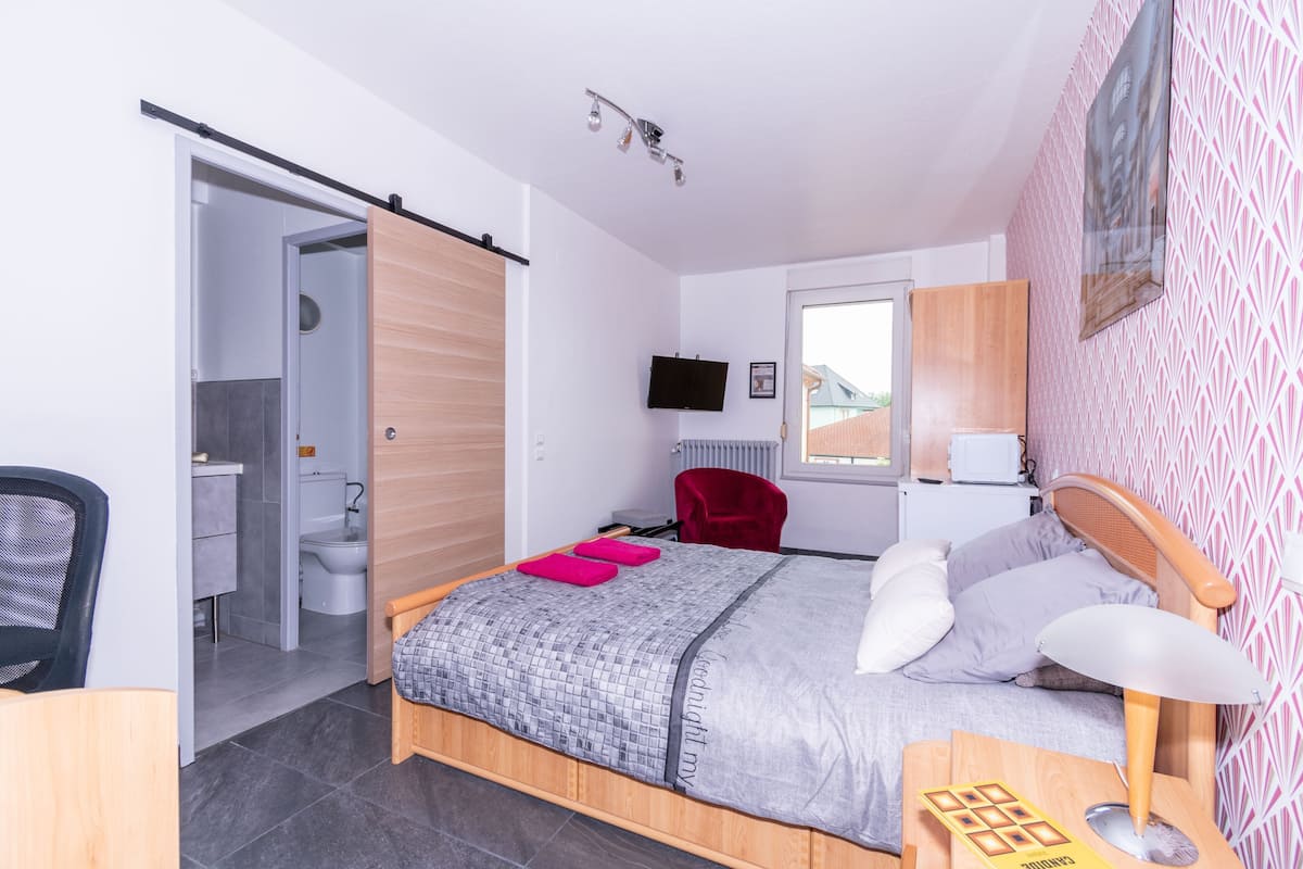 Een moderne slaapkamer met een bed, een bureau, een stoel, een televisie en een badkamer.