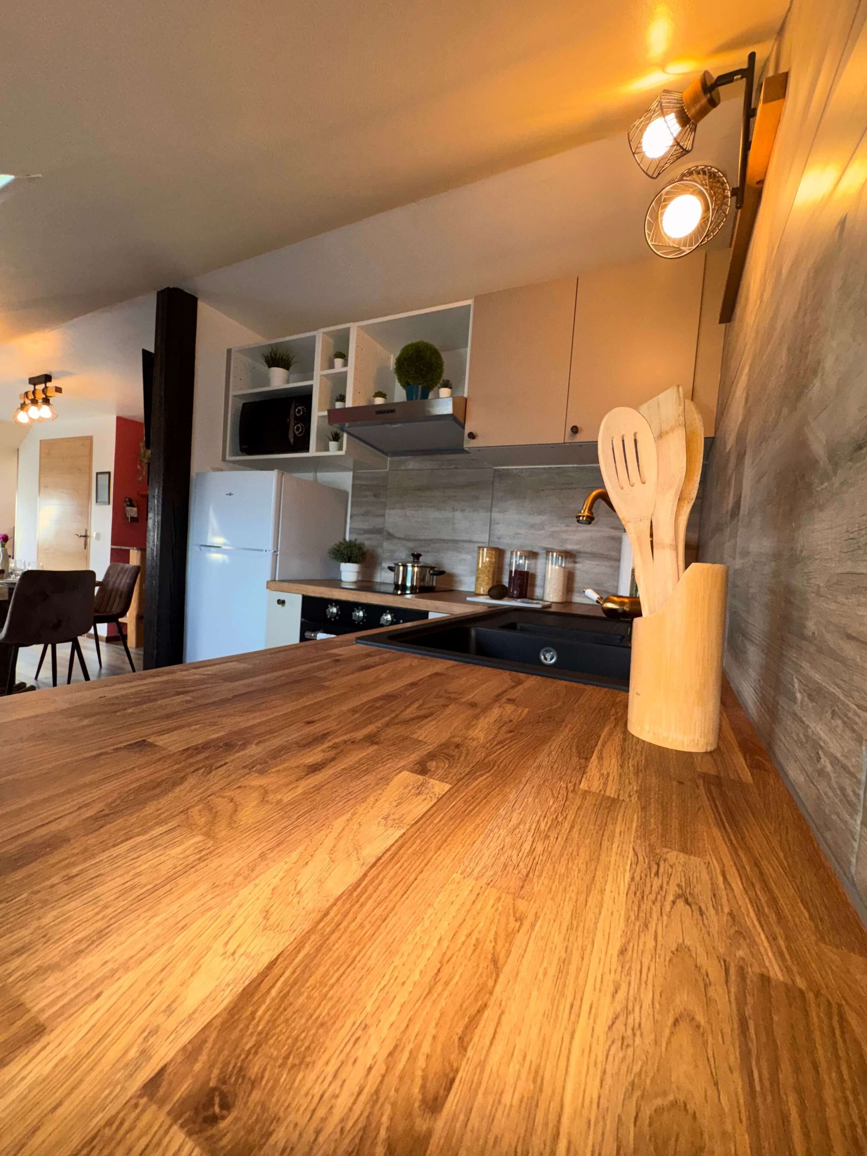 A modern kitchen with wooden countertops, a built-in microwave, and wooden utensils on the wall.