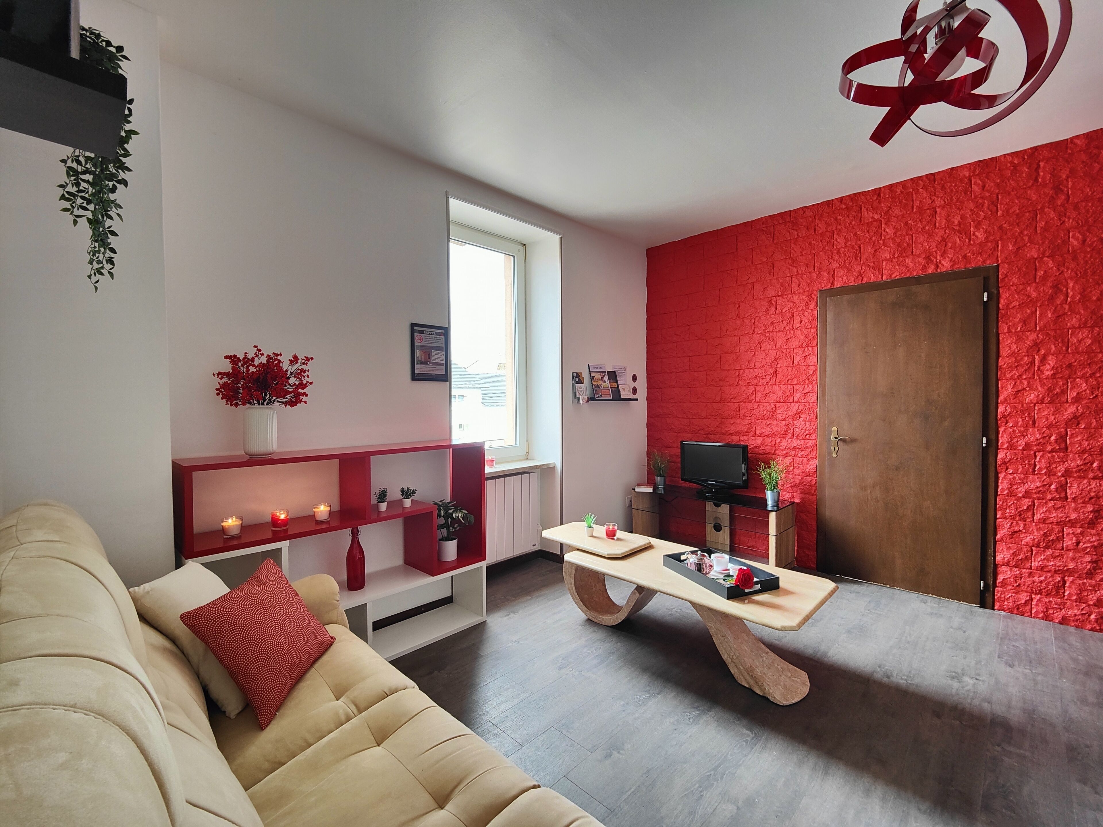 Una sala de estar moderna con un sofá color crema, una mesa de centro de madera y una pared decorativa de ladrillo rojo.