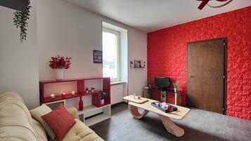 Una sala de estar moderna con un sofá color crema, una mesa de centro de madera y una pared decorativa de ladrillo rojo.