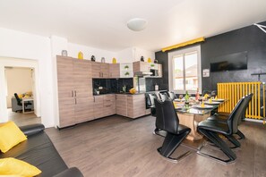 A modern kitchen with wooden cabinets, a black countertop, and a dining area with black chairs.