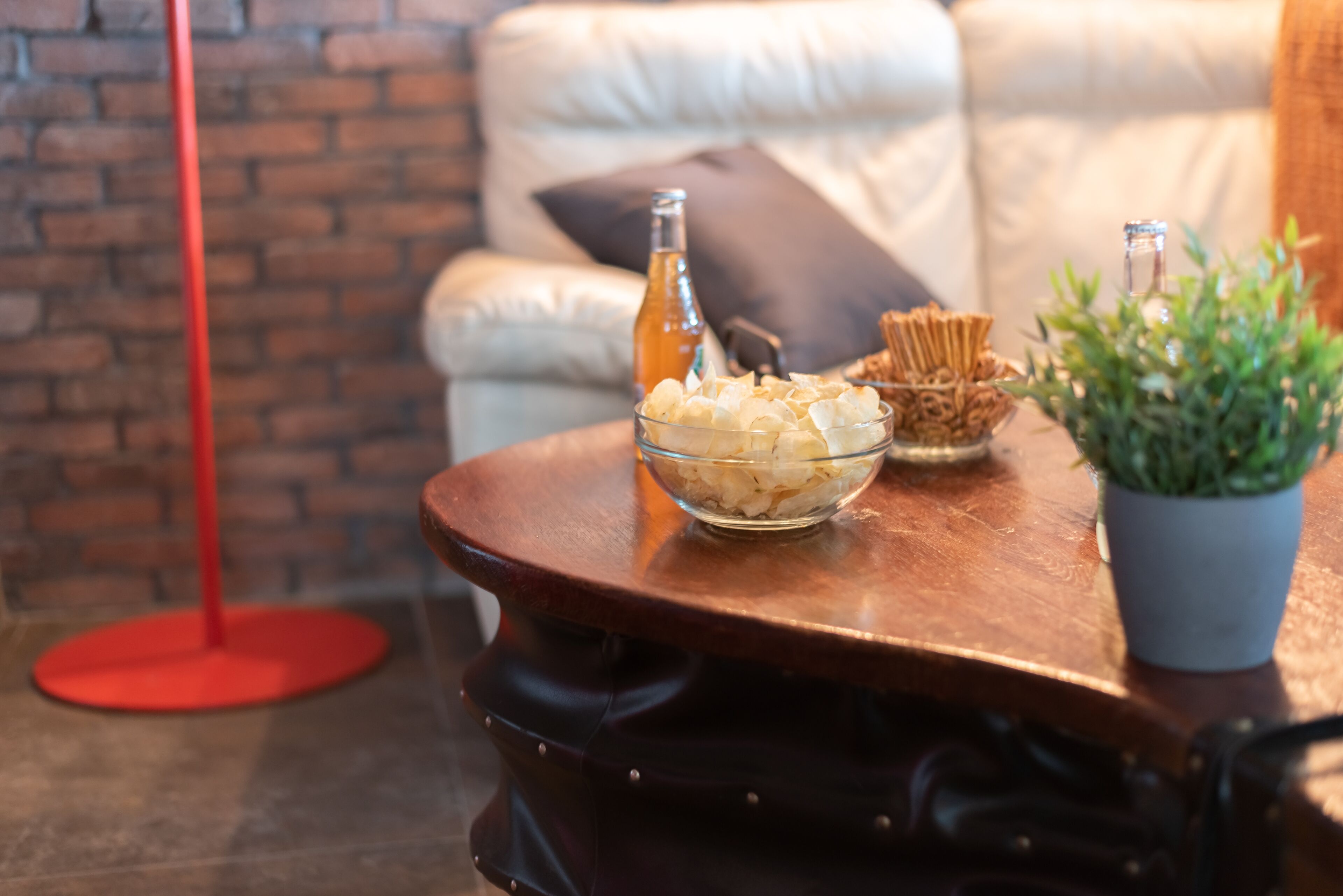Una mesa de madera con un tazón de bocadillos, una botella y una planta en maceta.