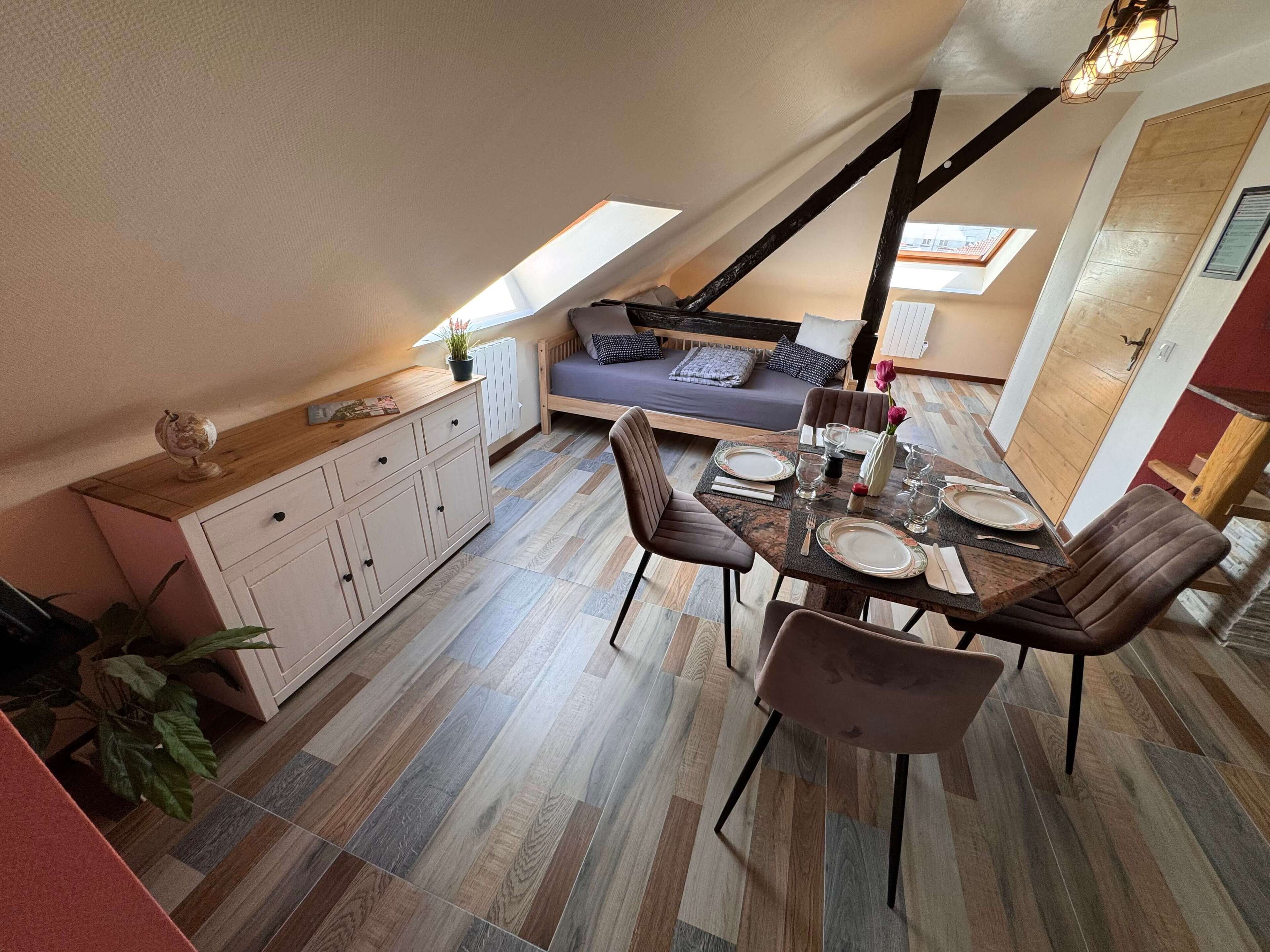 Un coin repas avec une table en bois dressée pour quatre personnes, un canapé et un meuble avec des tiroirs.