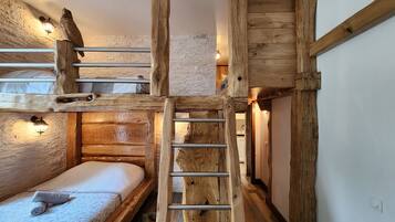 Una habitación rústica con literas, una escalera y pared de madera.