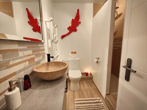 A modern bathroom with a large wooden basin, a toilet, and a shower area.