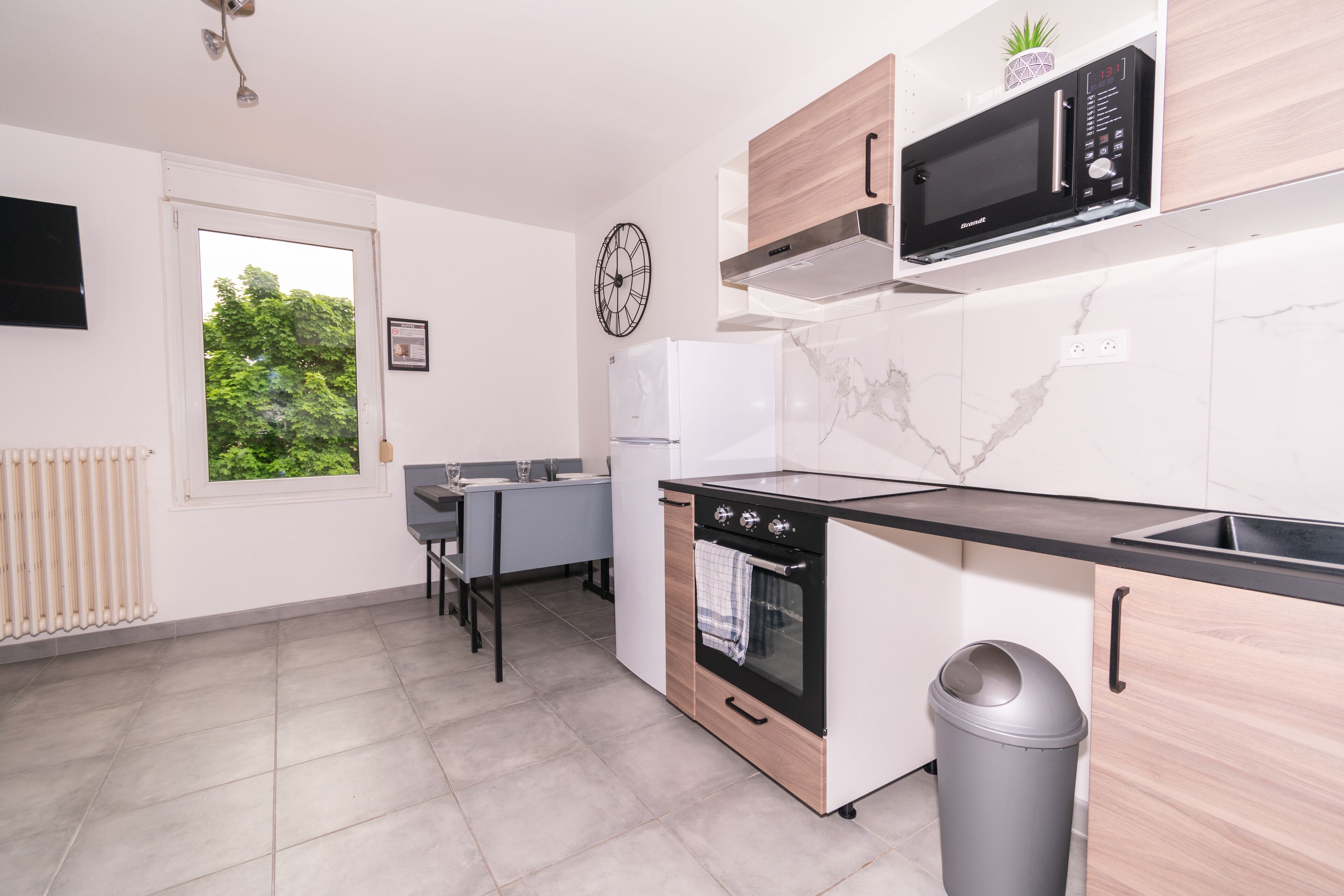 A modern kitchen with a built-in oven, microwave, and a small window.