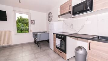 A modern kitchen with a built-in oven, microwave, and a small window.