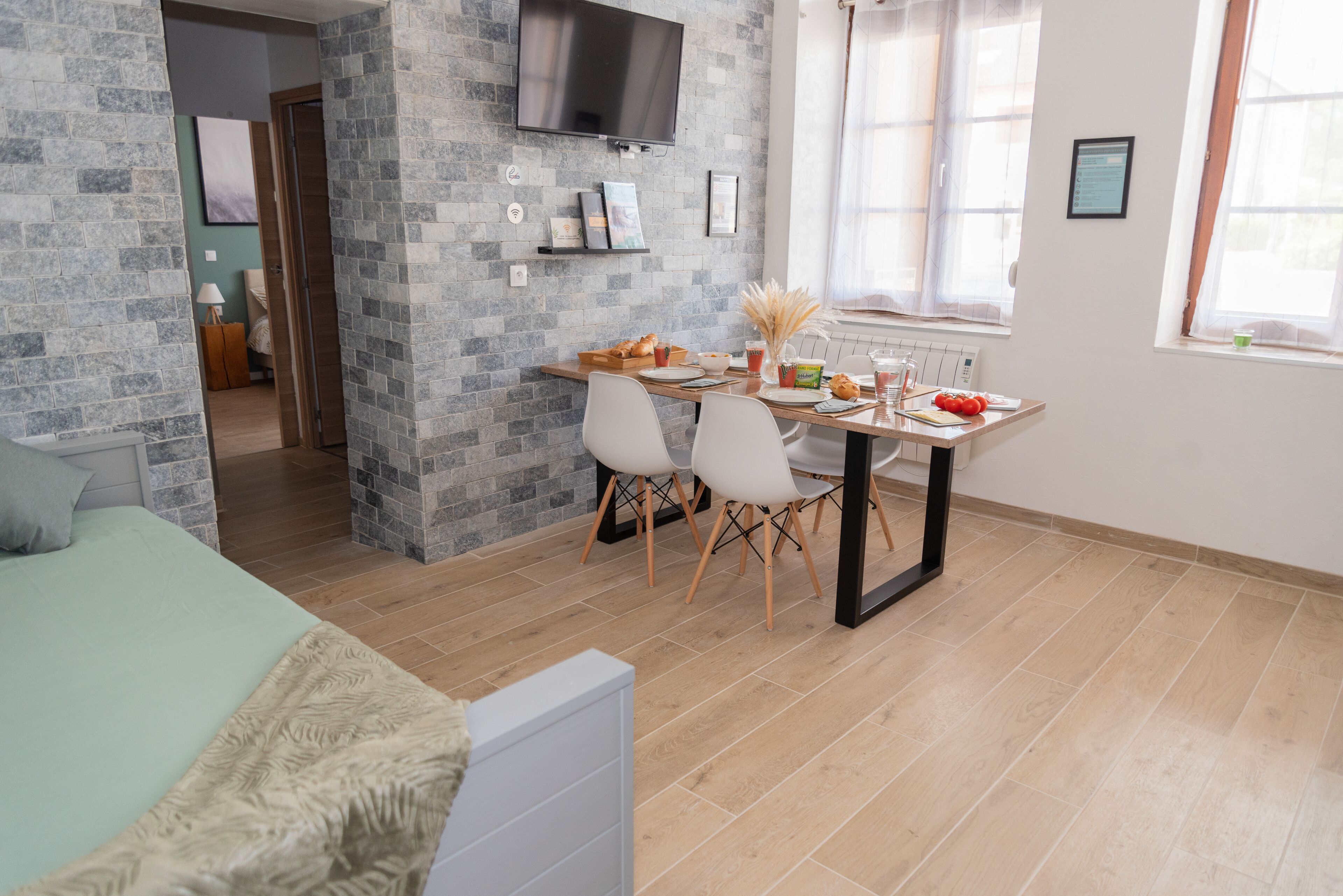 Ein modernes Zimmer mit Essbereich, einem Bett und einem an der Wand befestigten Fernseher.