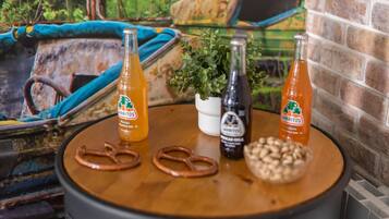 A table with two bottles of 'JARITOS' drink, two pretzels, a small bowl of nuts, and a potted plant.