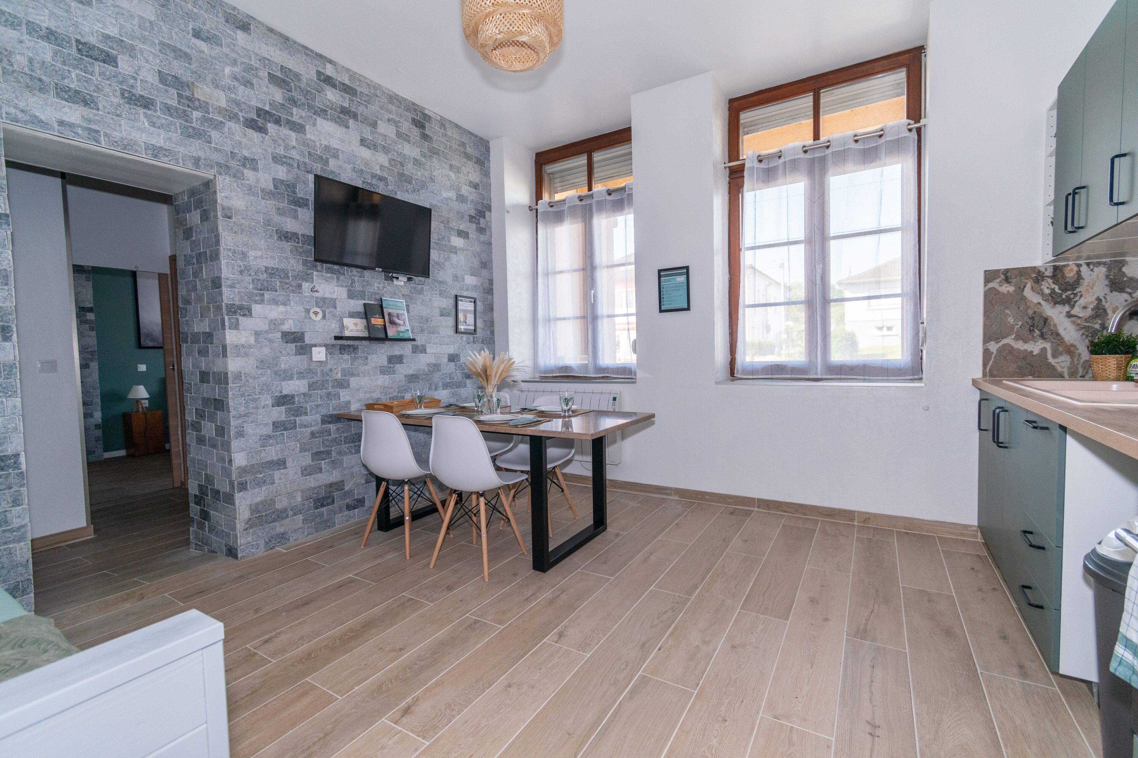 Una cocina moderna con salpicadero de piedra, un comedor con mesa y sillas, y un televisor montado en la pared.