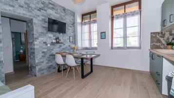 Una cocina moderna con salpicadero de piedra, un comedor con mesa y sillas, y un televisor montado en la pared.