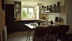 Une cuisine moderne dotée d’un îlot central, de tabourets de bar et offrant une vue sur l’extérieur.