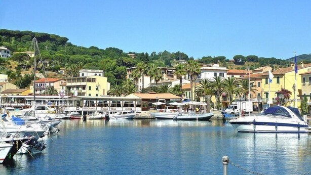 A marina with boats docked, surrounded by buildings with restaurants and shops. - Residence La Chiusa di Rio, Rio nell'Elba (Rio nell'Elba)