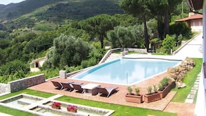 A swimming pool with a stone deck, lounge chairs, and a view of a mountainous landscape. - Residence La Chiusa di Rio, Rio nell'Elba (Rio nell'Elba)
