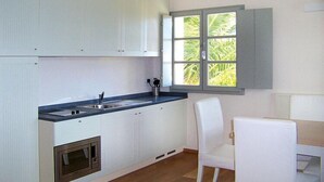 A modern kitchen with white cabinetry, a built-in oven, a sink, and a window with a view of greenery. - Residence La Chiusa di Rio, Rio nell'Elba (Rio nell'Elba)